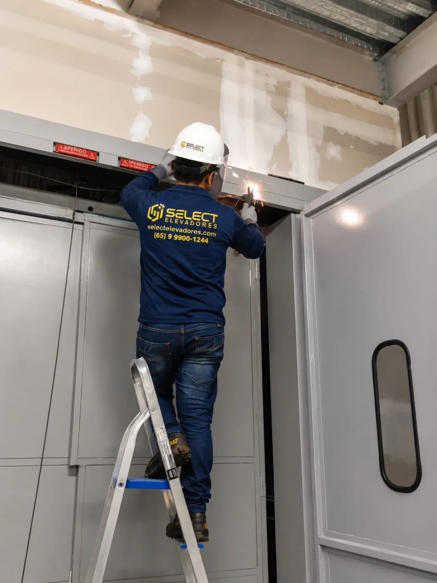 Técnico Select fazendo solda na estrutura superior do elevador