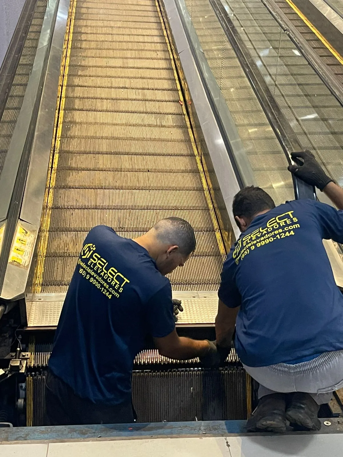 Manutenção em escada rolante com dois técnicos Select
